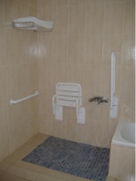 Ducha adaptada con asiento abatible y barras de agarre