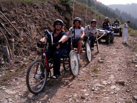 Varias personas con problemas de movilidad en las piernas paseando por la montaña en triciclos